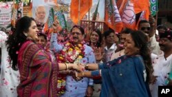 Supporters of India's ruling Bharatiya Janata Party celebrate India's Parliament Wednesday approving a bill providing a 10 percent quota in government jobs for poor upper caste members in Mumbai, India, Thursday, Jan 10, 2019.