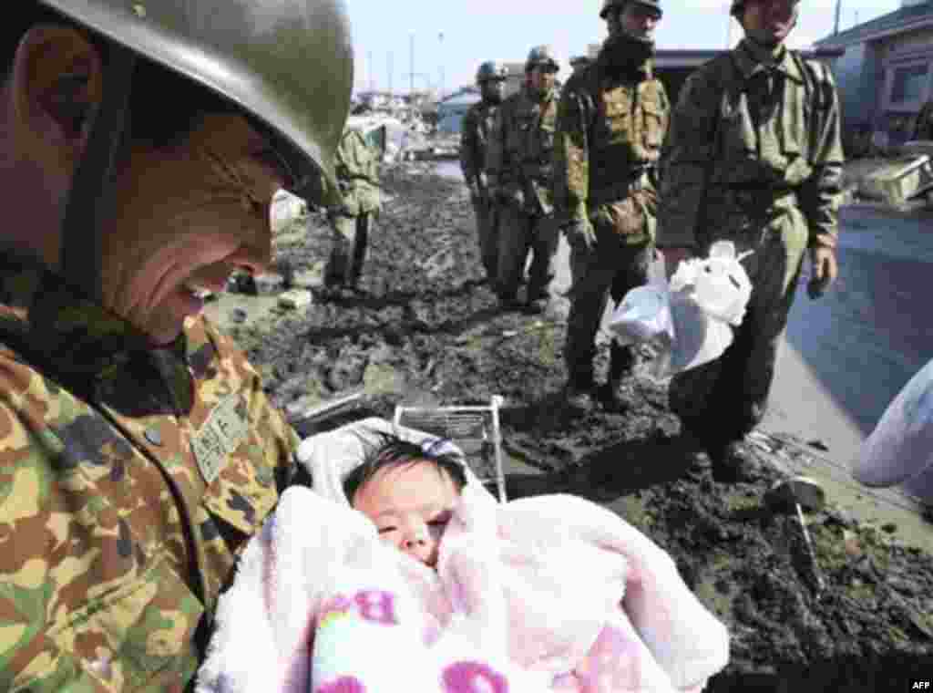 A Japan Self-Defense Force member reacts after rescuing a four-month-old baby girl in Ishinomaki, northern Japan, Monday, March 14, 2011, three days after a powerful earthquake-triggered tsunami hit the country's east coast. (AP Photo/The Yomiuri Shimbun,