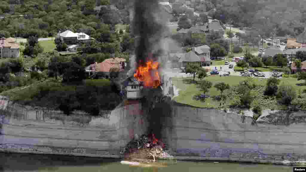 La fumée monte d&#39;une maison délibérément mis le feu, jour après qu&#39;une partie du terrain sur lequel elle reposait a effondré dans le lac Whitney, Texas, 13 juin 2014.