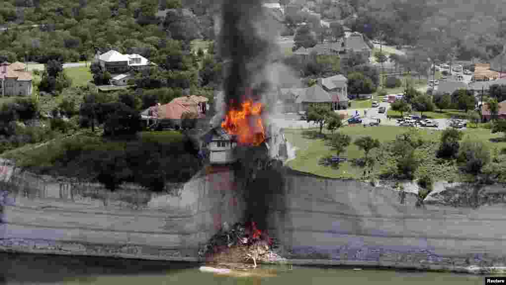 La fumée monte d'une maison délibérément mis le feu, jour après qu'une partie du terrain sur lequel elle reposait a effondré dans le lac Whitney, Texas, 13 juin 2014.