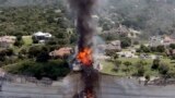 Smoke rises from a house deliberately set on fire, days after part of the ground it was resting on collapsed into Lake Whitney, Texas. Building crews set fire to the luxury lake house left dangling about 75 feet (23 meters) on a decaying cliff that has been giving way underneath the structure.
