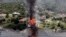Smoke rises from a house deliberately set on fire, days after part of the ground it was resting on collapsed into Lake Whitney, Texas. Building crews set fire to the luxury lake house left dangling about 75 feet (23 meters) on a decaying cliff that has been giving way underneath the structure.