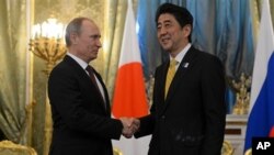 Presiden Rusia Vladimir Putin berjabat tangan dengan PM Jepang Shinzo Abe setibanya di Kremlin, Moskow (29/4).