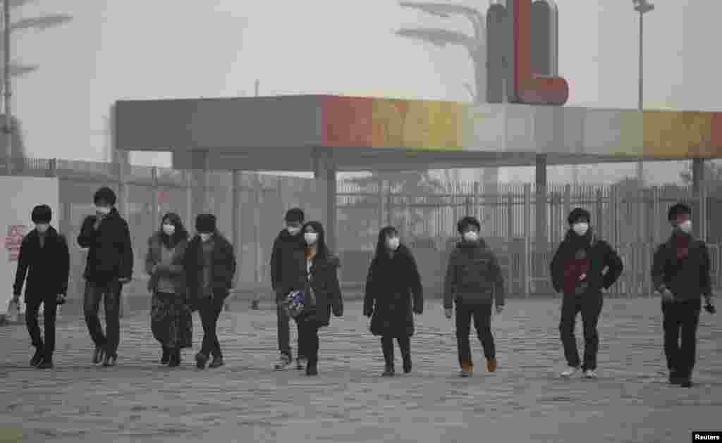 Japanese tourists wearing masks make their way to the Olympic Park amid thick haze in Beijing, Feb. 25, 2014. 