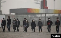 日本游客带着口罩在浓重的雾霾中走向北京的奥林匹克公园（2014年2月25日）