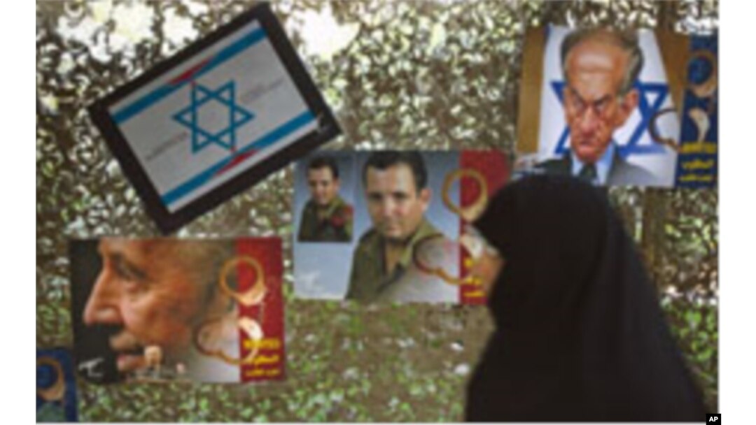 A woman walks past anti-Israel posters depicting Israel's President Shimon Peres, Defense Minister Ehud Barak and a caricature of Prime Minister Benjamin Netanyahu (L-R) as she visits a war exhibition held by Iran's revolutionary guard, at Baharestan squa