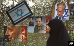A woman walks past anti-Israel posters depicting Israel's President Shimon Peres, Defense Minister Ehud Barak and a caricature of Prime Minister Benjamin Netanyahu (L-R) as she visits a war exhibition held by Iran's revolutionary guard, at Baharestan squa