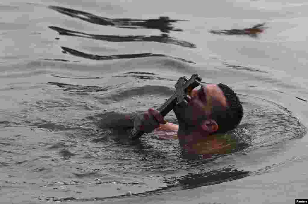 Greek Orthodox faithful Nikolas Solis, 28, a pilgrim from Agrinio of Greece, kisses a wooden crucifix in the Golden Horn in Istanbul, Turkey.