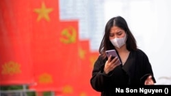 In this Jan. 23, 2021, file photo, a woman wearing face mask looks at her phone. Amnesty International has found that a hacking group known as Ocean Lotus has been digitally attacking Vietnamese human rights activists in the communist-ruled country. (AP Photo/Hau Dinh, File)