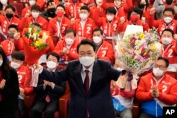 Presiden terpilih Korea Selatan Yoon Suk-yeol memegang karangan bunga saat dia diberi ucapan selamat atas kemenangannya oleh anggota partai dan anggota parlemen di Majelis Nasional di Seoul, Korea Selatan, 10 Maret 2022. (Foto: AP)