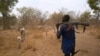 FILE - An armed cattle keeper walks with his cows during a seasonal migration of cattle for grazing near Tonj, South Sudan, Feb. 16, 2020.