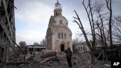 A Ukrainian serviceman takes a photograph of a damaged church after shelling in a residential district in Mariupol, Ukraine, March 10, 2022.