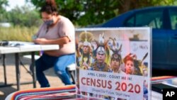 FILE - A sign promoting Native American participation in the U.S. census is displayed as Selena Rides Horse enters information into her phone on behalf of a member of the Crow Indian Tribe in Lodge Grass, Mont., on Aug. 26, 2020.