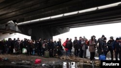 People flee under a destroyed bridge to cross the Irpin River, in Irpin outside Kyiv, Ukraine, March 9, 2022. 