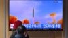 FILE - People watch a television screen showing a news broadcast with file footage of a North Korean missile test, at a railway station in Seoul, March 5, 2022.