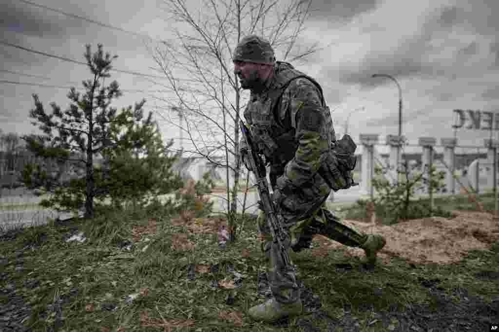 A Ukrainian serviceman takes a shooting position as he looks at approaching vehicles in Irpin, March 9, 2022.