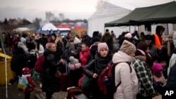 Refugees wait for a bus after crossing from Ukraine in Medyka, Poland, March 9, 2022.