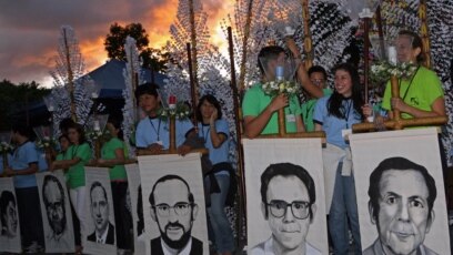 Estudiantes de la Universidad Centroamericana José Simeón Cañas sostienen retratos de los seis sacerdotes jesuitas de España asesinados por el ejército salvadoreño durante la guerra civil en 1989, mientras participan en una ceremonia de homenaje. [Foto de archivo]