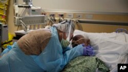 A woman weeps while hugging her husband in his final moments in a COVID-19 unit at St. Jude Medical Center in Fullerton, Calif., July 31, 2020. 