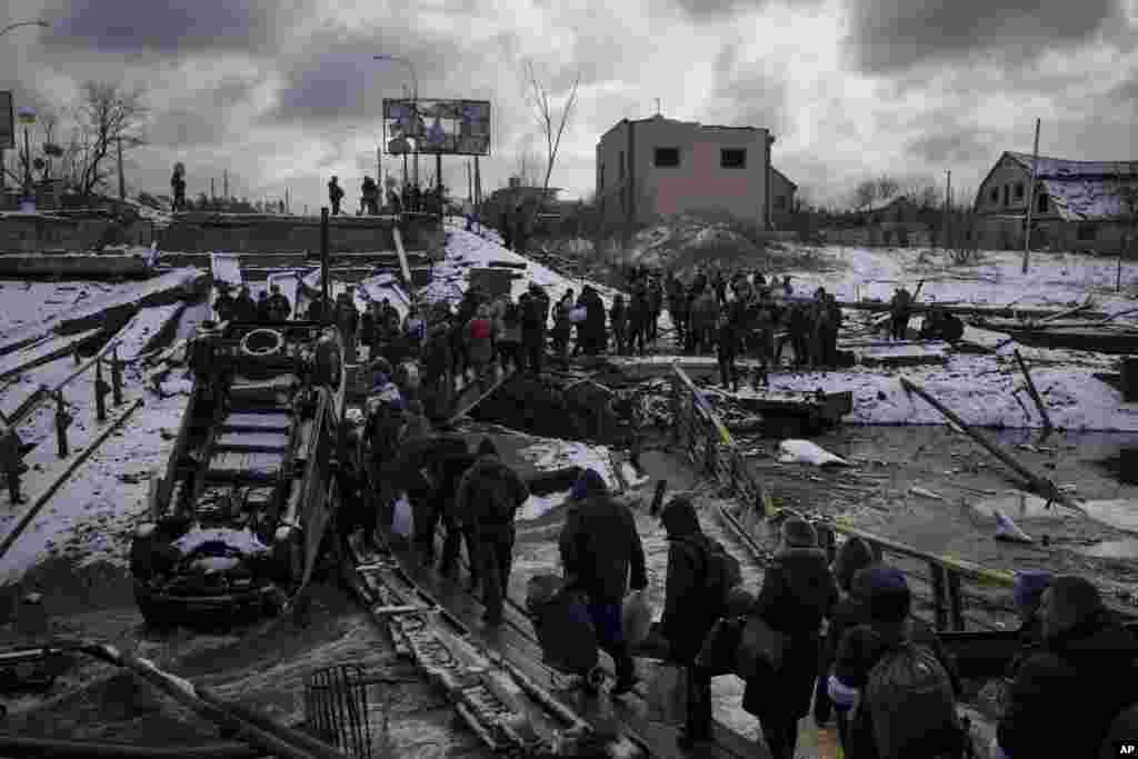 Ukrainians cross an improvised path under a destroyed bridge while fleeing Irpin, March 8, 2022.&nbsp;Demands for ways to safely evacuate civilians have surged along with intensifying shelling by Russian forces, who have made significant advances in southern Ukraine but stalled in some other regions.