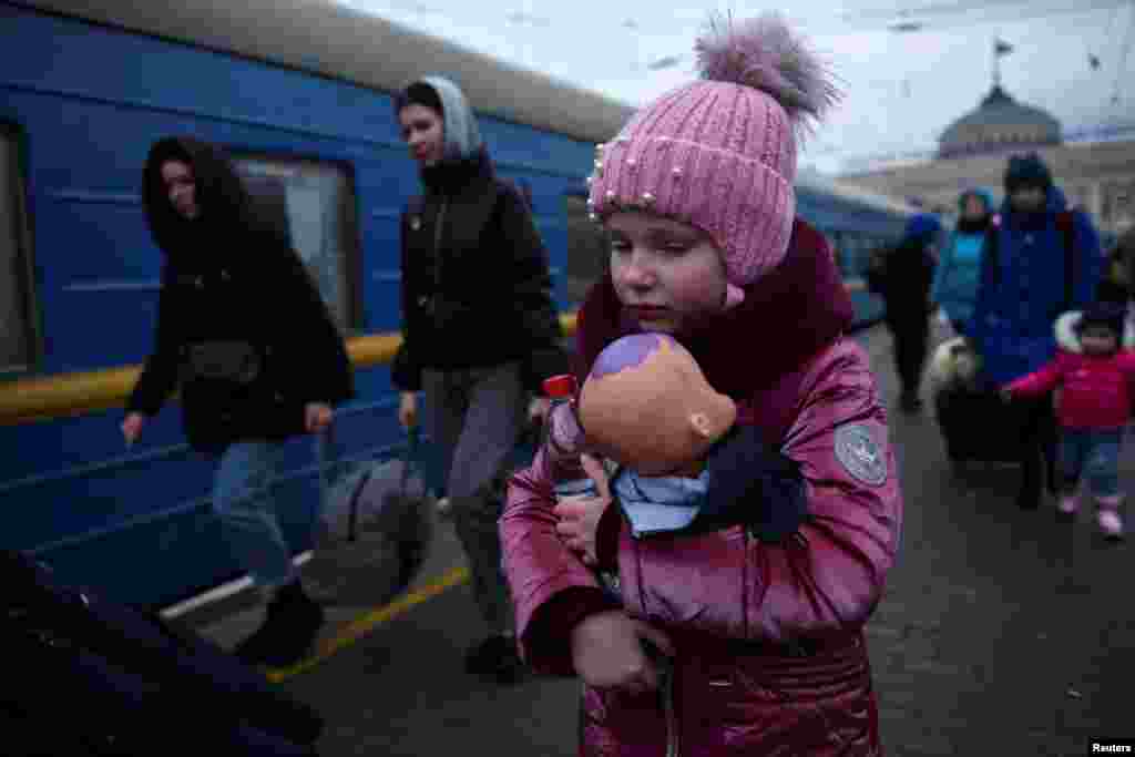 A girl holds a doll as civilians fleeing Russia&#39;s invasion of Ukraine board a train, in Odessa, March 8, 2022.