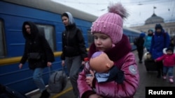 FILE - A girl holds a doll as civilians fleeing Russia's invasion of Ukraine board a train, in Odessa, Ukraine, March 8, 2022.