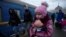 FILE - A girl holds a doll as civilians fleeing Russia's invasion of Ukraine board a train, in Odessa, Ukraine, March 8, 2022.