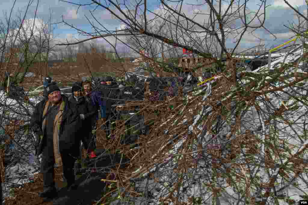 Civilians that were trapped in the little town of Irpin escape from the battles through an improvised path created alongside a bombed bridge by Ukrainian forces, in Irpin, Ukraine, March 8, 2022. (Yan Boechat/VOA)