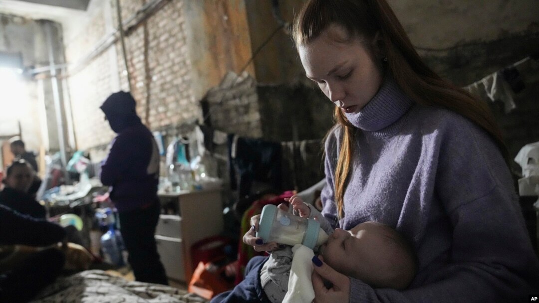 A young woman feeds a baby in a makeshift bomb shelter in Mariupol, Ukraine, March 7, 2022.