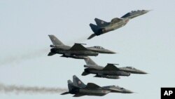 FILE - Two Polish Air Force Russian-made MiG 29s fly above and below two Polish Air Force U.S.-made F-16 fighter jets during an air show in Radom, Poland, Aug. 27, 2011.