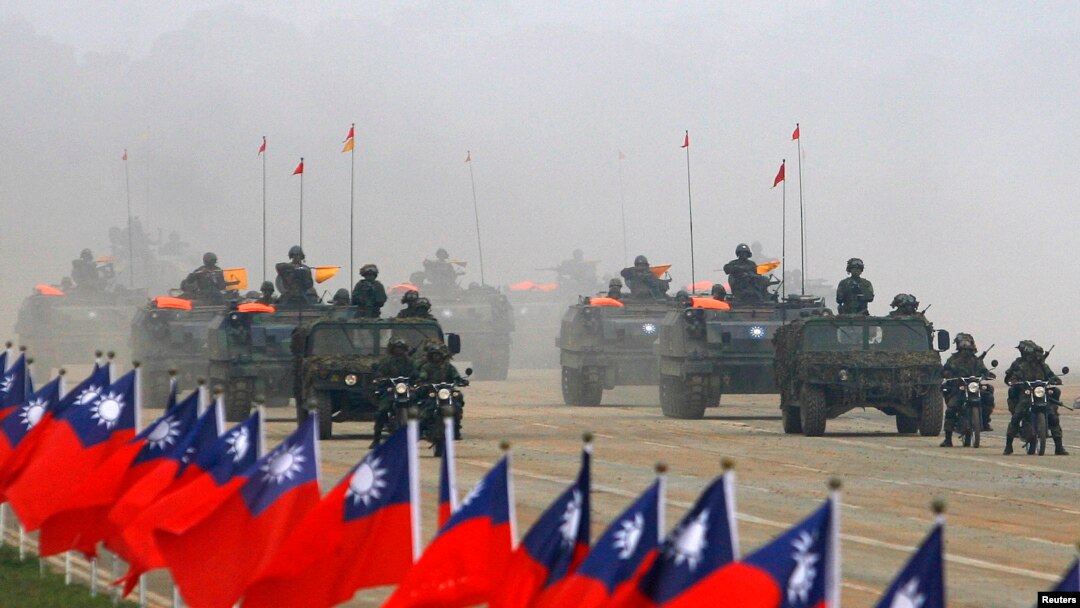 Tentara Taiwan mengendarai kendaraan militer mereka melewati bendera negaranya saat latihan militer di Hsinchu, Taiwan tengah 27 Januari 2010. (REUTERS/Nicky Loh) 