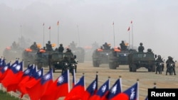 Tentara Taiwan mengendarai kendaraan militer mereka melewati bendera negaranya saat latihan militer di Hsinchu, Taiwan tengah 27 Januari 2010. (REUTERS/Nicky Loh) 