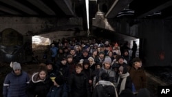 Ukrainians crowd under a destroyed bridge as they try to flee crossing the Irpin river in the outskirts of Kyiv, Ukraine, March 8, 2022. 