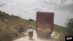 Un chauffeur de mototaxi transportant un soldat congolais et une femme tente de dépasser un camion sur une route menant à Bunia le 8 janvier 2022 dans la province méridionale de l'Ituri, dans le nord-est de la République démocratique du Congo.