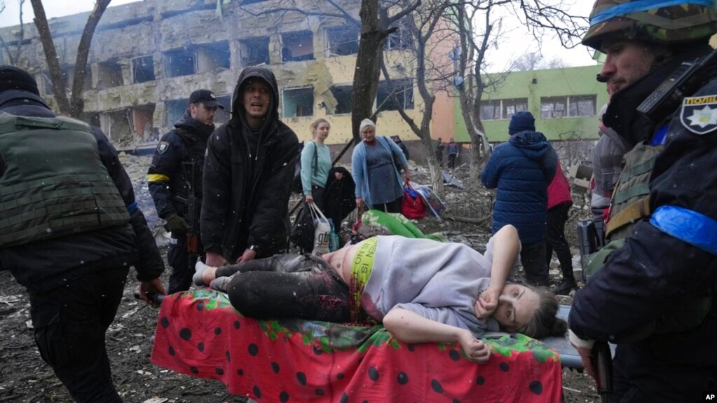 Ukrainian emergency employees and volunteers carry an injured pregnant woman from a maternity hospital damaged by shelling in Mariupol, Ukraine, March 9, 2022. (AP Photo/Evgeniy Maloletka)