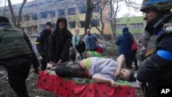 9일 우크라이나 남부 항구도시 마리우폴의 어린이·산부인과 병원 폭격 현장에서 부상당한 임신부를 구조요원들이 이송하고 있다.