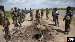 Des soldats somaliens sur le lieu de l'explosion d'une voiture piégée à un point de contrôle près de la base militaire de Sanguuni, en Somalie, le 13 juin 2018. / PHOTO AFP / Mohamed ABDIWAHAB
