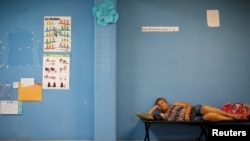 A woman rests in a school used as a shelter before the arrival of the Hurricane Maria in Guayama, Puerto Rico, Sept. 19, 2017.