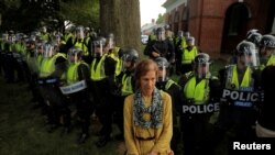 Una manifestante parada frente a oficiales de policía del estado de Virginia que forman un cordón en la Universidad de Virginia, antes del primer aniversario de las protestas de Charlottesville 2017 "Unite the Right", en Charlottesville, Virginia, el 11 de agosto de 2018.