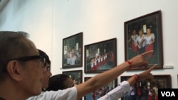 Visitors point to photos of Em Theay, now 85, taken by photographer Aray Steven, on display at National Museum in Phnom Penh, November 1, 2015. (Photo: Phorn Bopha/VOA Khmer) 