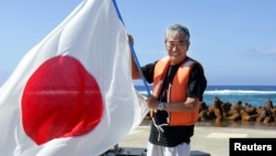 资料照：前东京都知事石原慎太郎在冲之鸟岛上挥舞日本旗帜。（2005年5月20日）