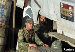 FILE - Syrian army soldiers stand at a check-point near village of Qum el Mayadine, Syria, Aug. 14, 2018.