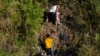 A Venezuelan migrant grips a child as he climbs a river bank onto U.S territory, after crossing from Matamoros, Mexico, Dec. 22, 2022.