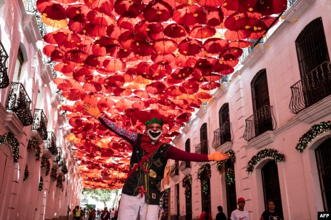 Un hombre sobre zancos vestido como un personaje navideño actúa para los turistas que visitan el centro histórico de Caracas el 30 de diciembre de 2022, en la víspera de las celebraciones de fin de año. [AFP]