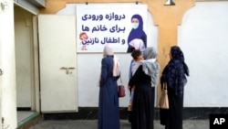 FILE - Afghan women stand outside an amusement park, in Kabul, Nov. 10, 2022. The Taliban ordered NGOs to suspend Afghan female staff for allegedly not wearing the Islamic hijab and breaching mandatory gender segregation at work.