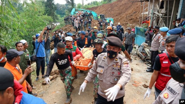 Rescuers carry the body of a victim recovered from under the rubble at a village affected by an earthquake-triggered landslide in Cianjur, West Java, Indonesia, Tuesday, Nov. 22, 2022. (AP Photo/Rangga Firmansyah)
