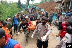 Tim penyelamat membawa jenazah korban yang ditemukan dari bawah reruntuhan di sebuah desa yang terkena tanah longsor akibat gempa bumi di Cianjur, Jawa Barat, Selasa, 22 November 2022.(AP Photo/Rangga Firmansyah)