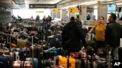 Travelers wade through unclaimed baggage near the Southwest Airlines baggage carousels at Denver International Airport, Dec. 27, 2022. 