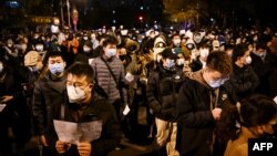 Protesters march along a street during a rally for the victims of a deadly fire as well as a protest against China's harsh Covid-19 restrictions in Beijing on Nov. 28, 2022. 