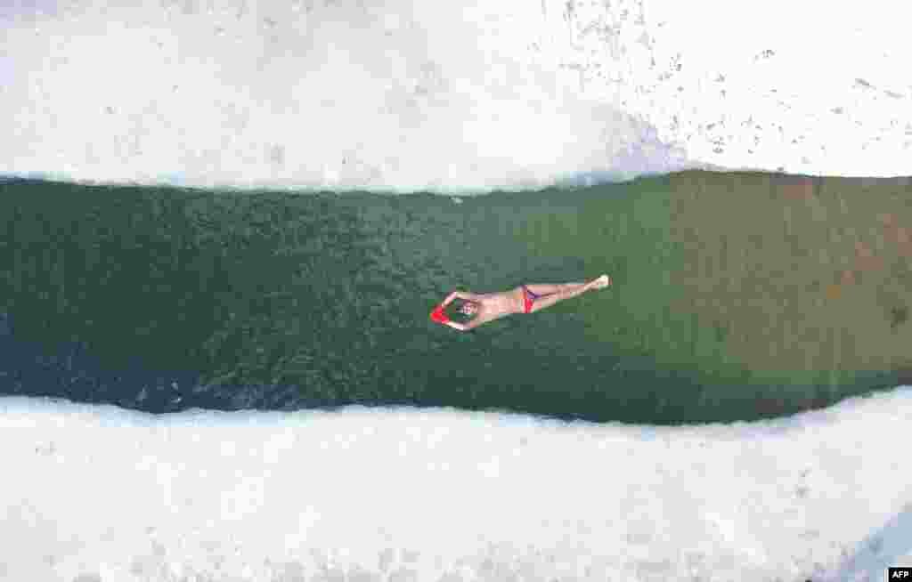 Зимски пливач плива во делумно замрзнато езеро по снежните врнежи во Шенјанг, во североисточната кинеска провинција Лиаонинг.